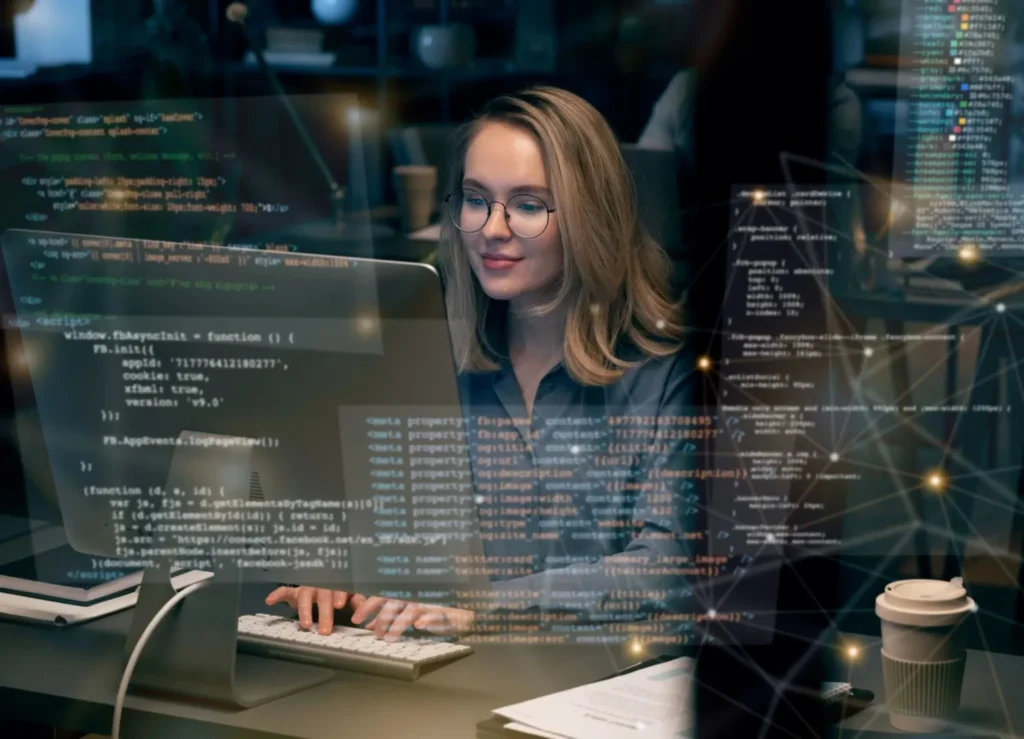 A focused woman wearing glasses working on a computer screen displaying code and data, representing a professional engaged in full stack website development.