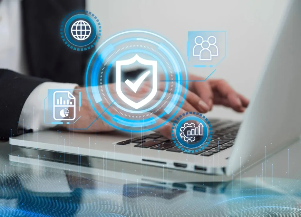 Close-up of hands typing on a laptop with a glowing digital overlay featuring a shield icon and security-related icons (globe, users, documents, settings/gear), symbolizing securing your website, a key part of website development.