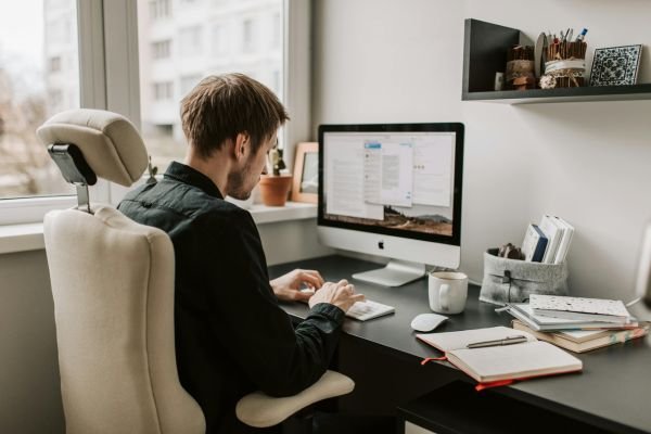 A man sitting at a desk with a computer and notebook, working on digital marketing and local search ranking factors.