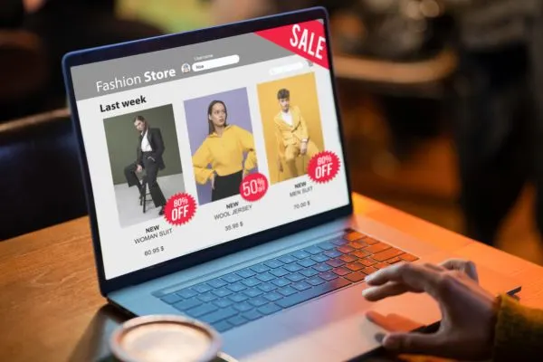 Close-up of a laptop displaying a fashion store website with clothing discounts. Consider ecommerce website development cost.